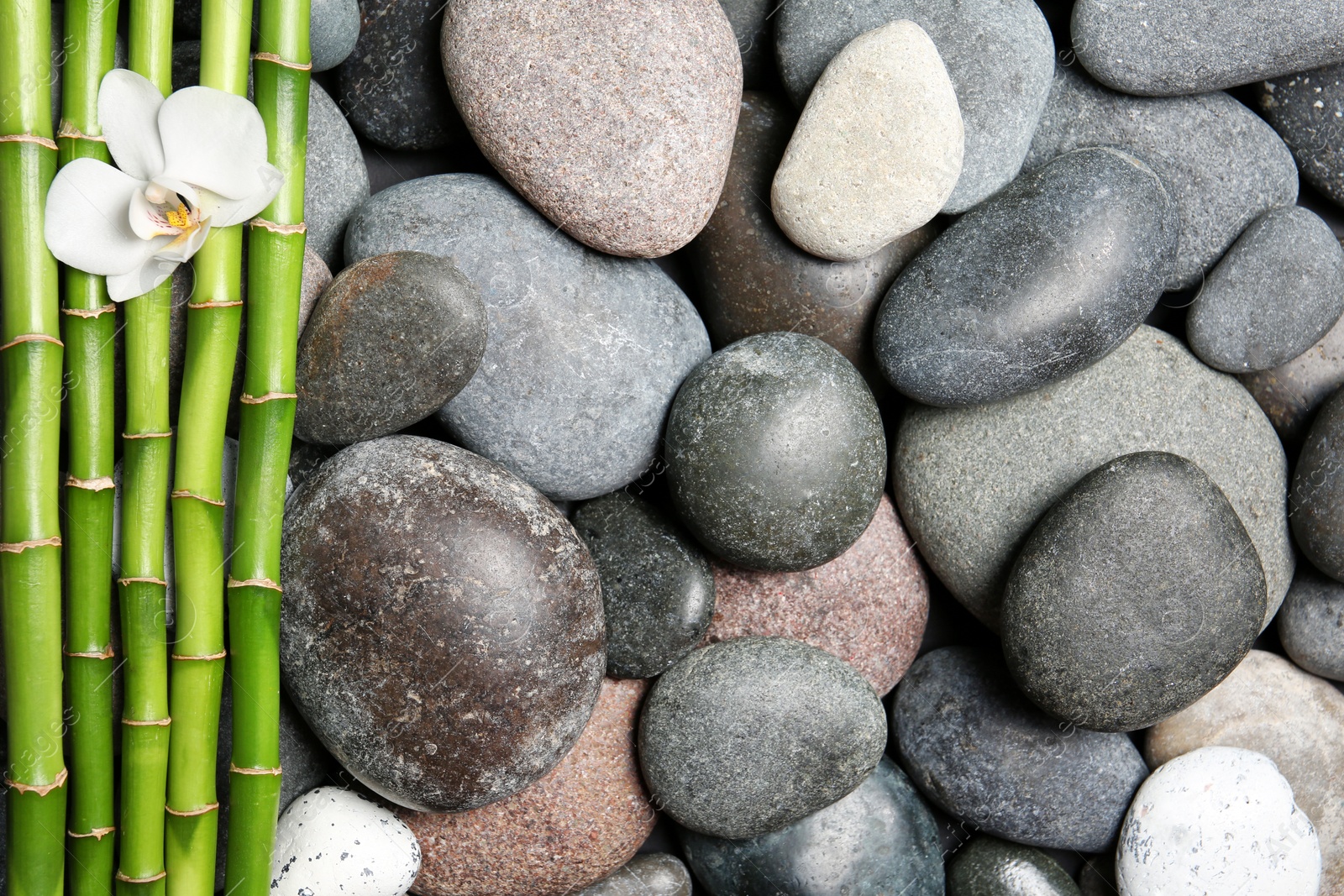 Photo of Composition with spa stones and bamboo branches as background, top view