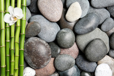 Photo of Composition with spa stones and bamboo branches as background, top view