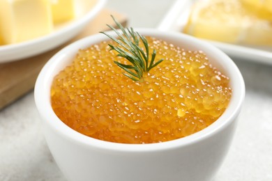 Photo of Fresh pike caviar and dill in bowl on light grey table, closeup
