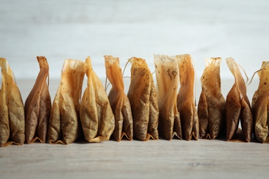 Many used tea bags on wooden table, closeup