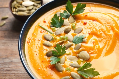 Photo of Delicious pumpkin cream soup in bowl on table, closeup