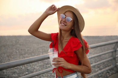 Photo of Beautiful young woman with tasty milk shake outdoors
