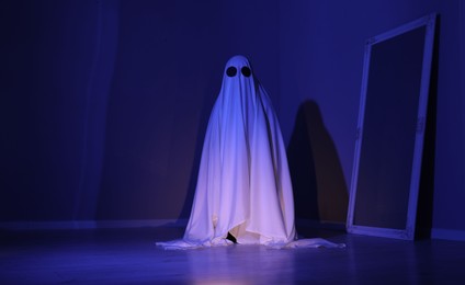 Photo of Creepy ghost. Woman covered with sheet in blue light, space for text