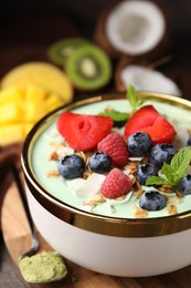 Tasty matcha smoothie bowl served with berries and oatmeal on table, closeup. Healthy breakfast