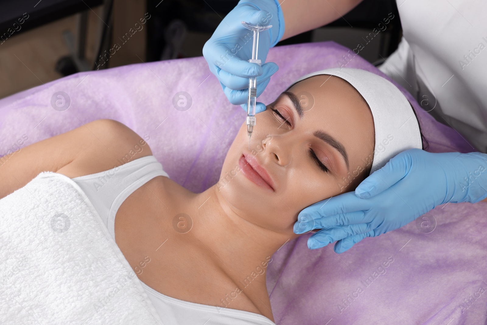 Photo of Young woman getting facial injection in beauty salon. Cosmetic procedure