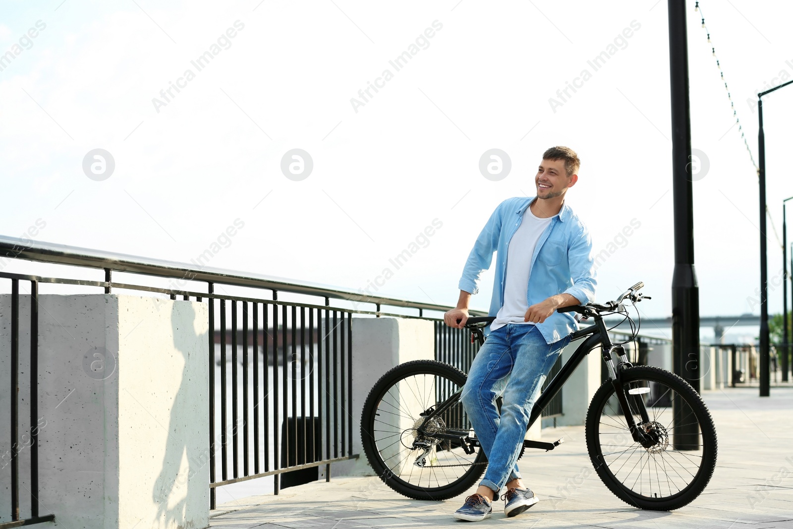 Photo of Handsome man with modern bicycle near river