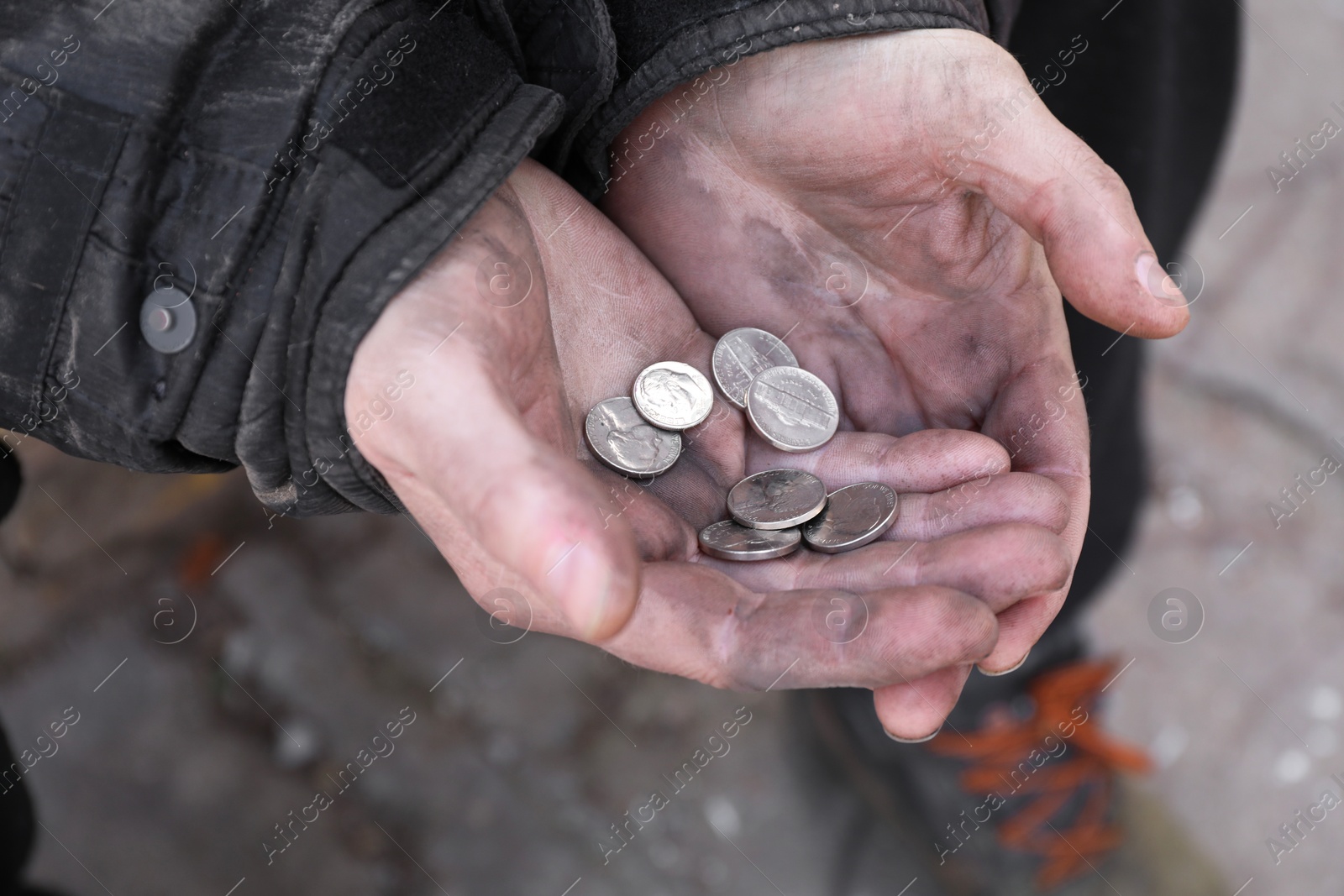 Photo of Poor homeless man holding coins outdoors, closeup