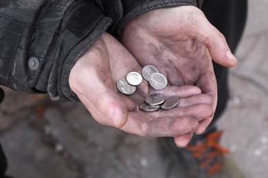 Photo of Poor homeless man holding coins outdoors, closeup