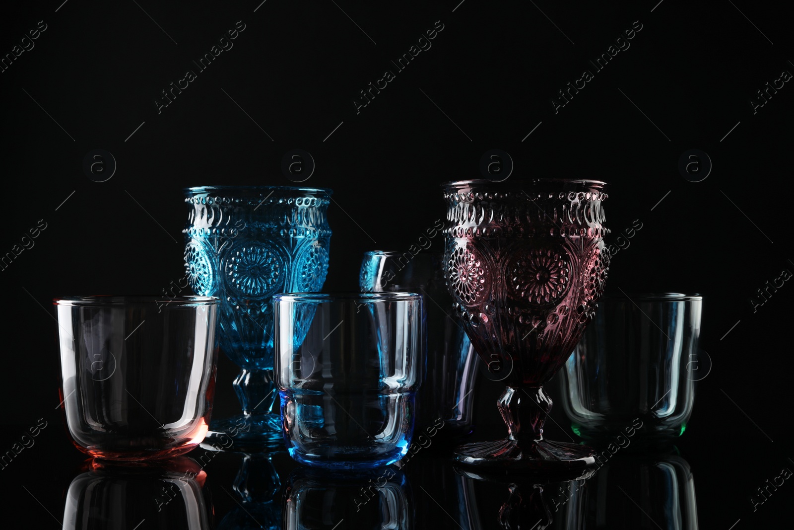 Photo of Set of different colorful empty glasses on black background