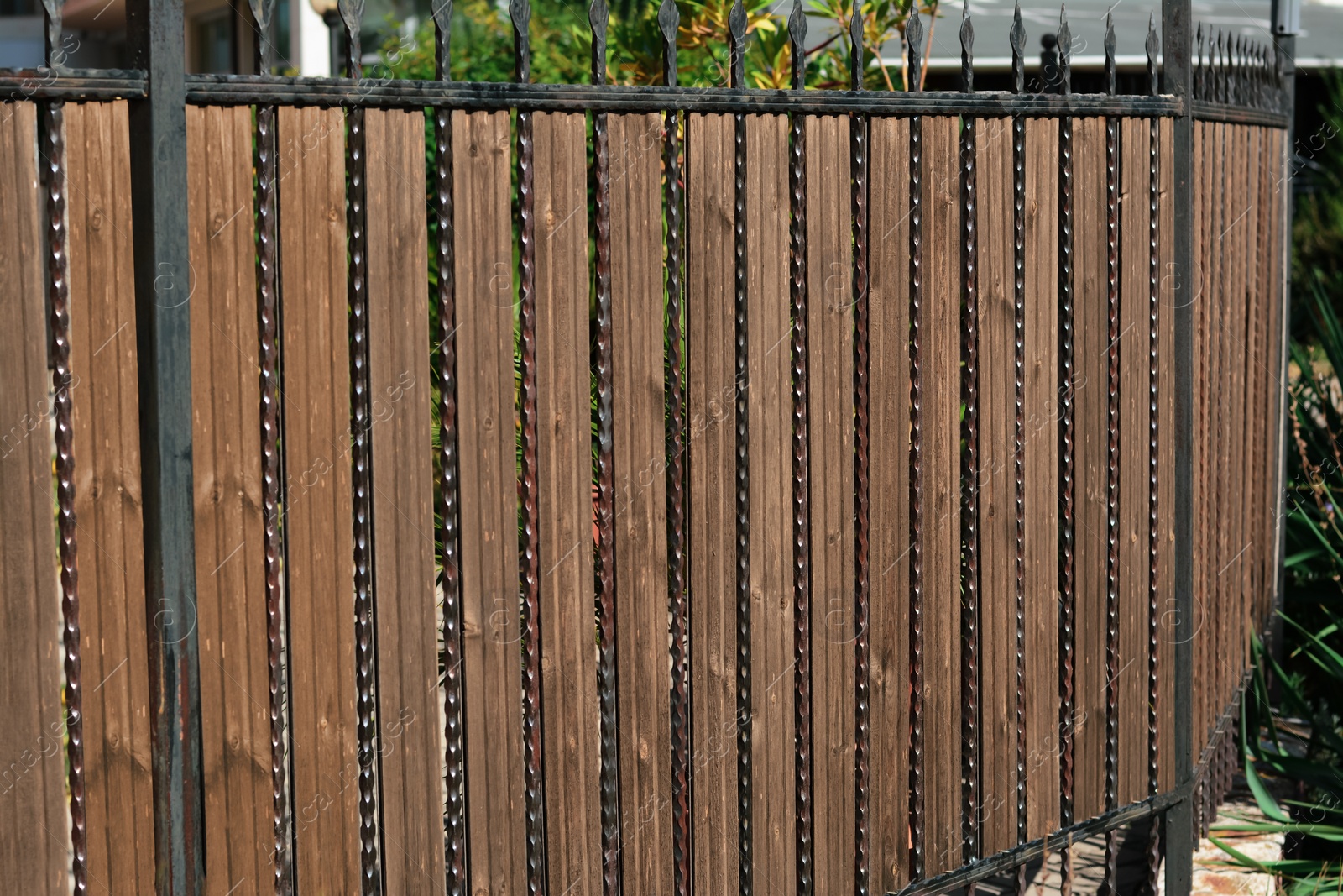 Photo of Metal and wooden fence outdoors on sunny day