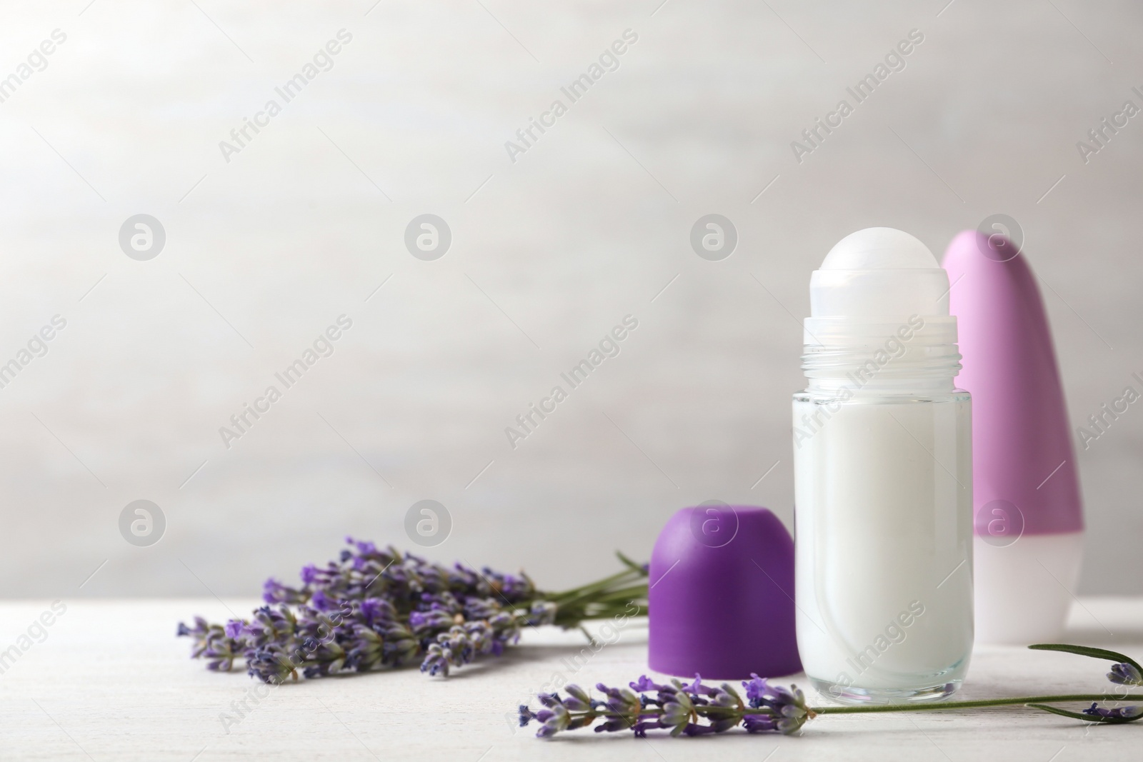 Photo of Female deodorants and lavender flowers on white wooden table. Space for text