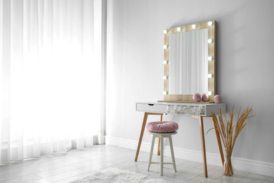 Photo of Stylish mirror with lamps near light wall in room