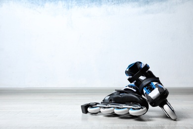 Inline roller skates on floor near color wall. Space for text
