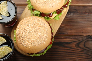 Photo of Delicious cheeseburgers and drinks on wooden table, top view. Space for text