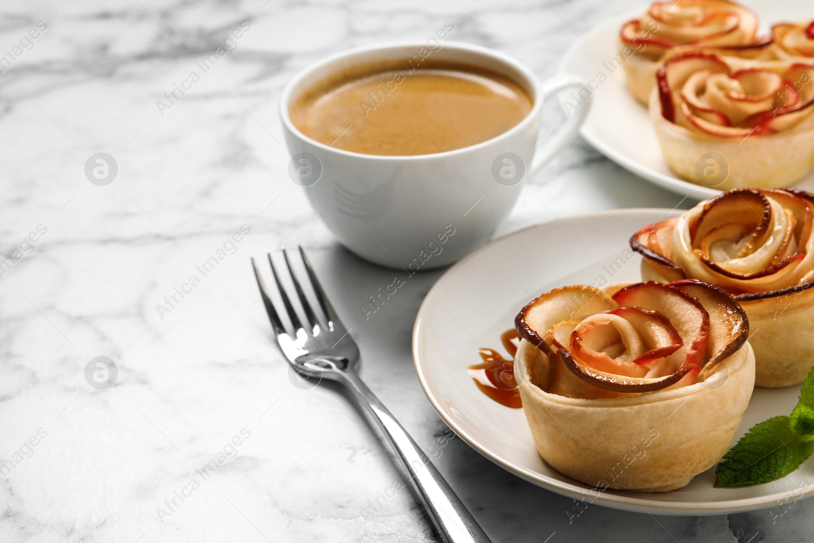 Photo of Freshly baked apple roses served on white marble table, space for text. Beautiful dessert