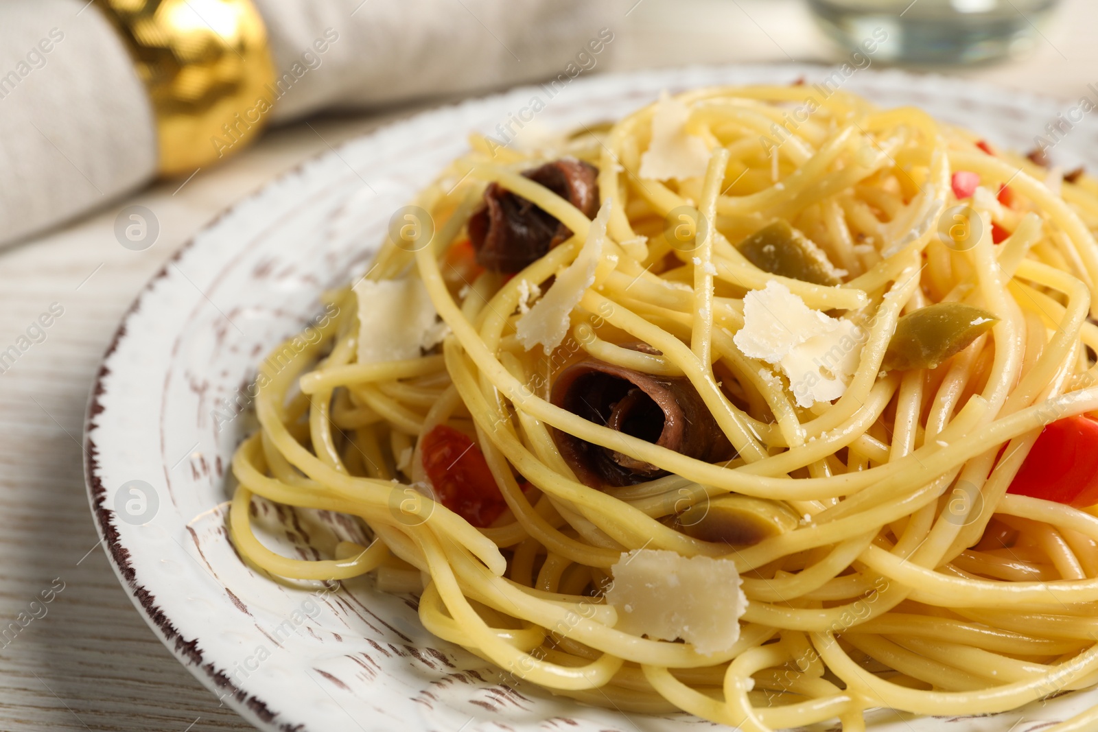 Photo of Delicious pasta with anchovies, tomatoes and parmesan cheese served on white wooden table, closeup