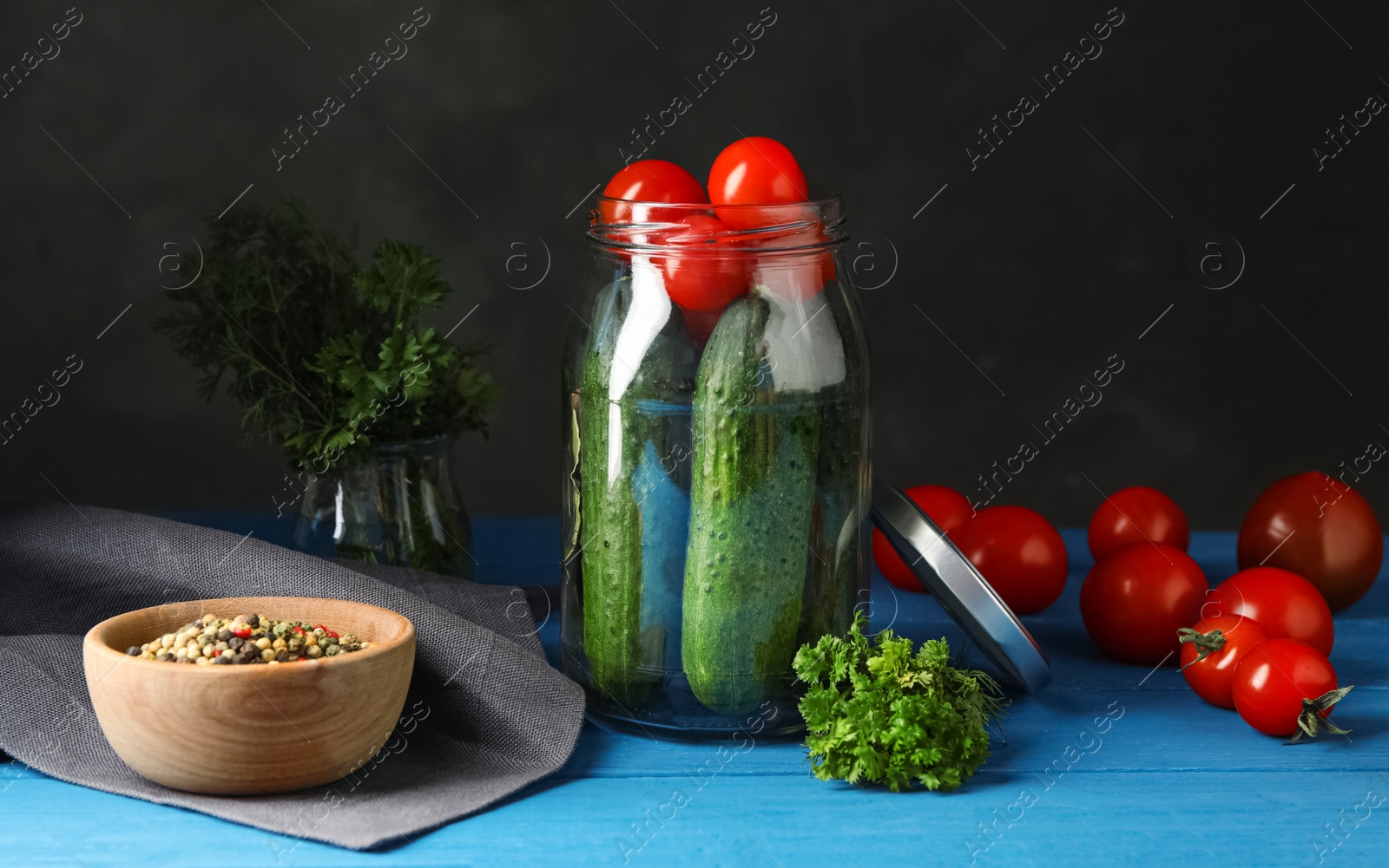 Photo of Pickling jar with fresh ripe vegetables and spices on blue wooden table