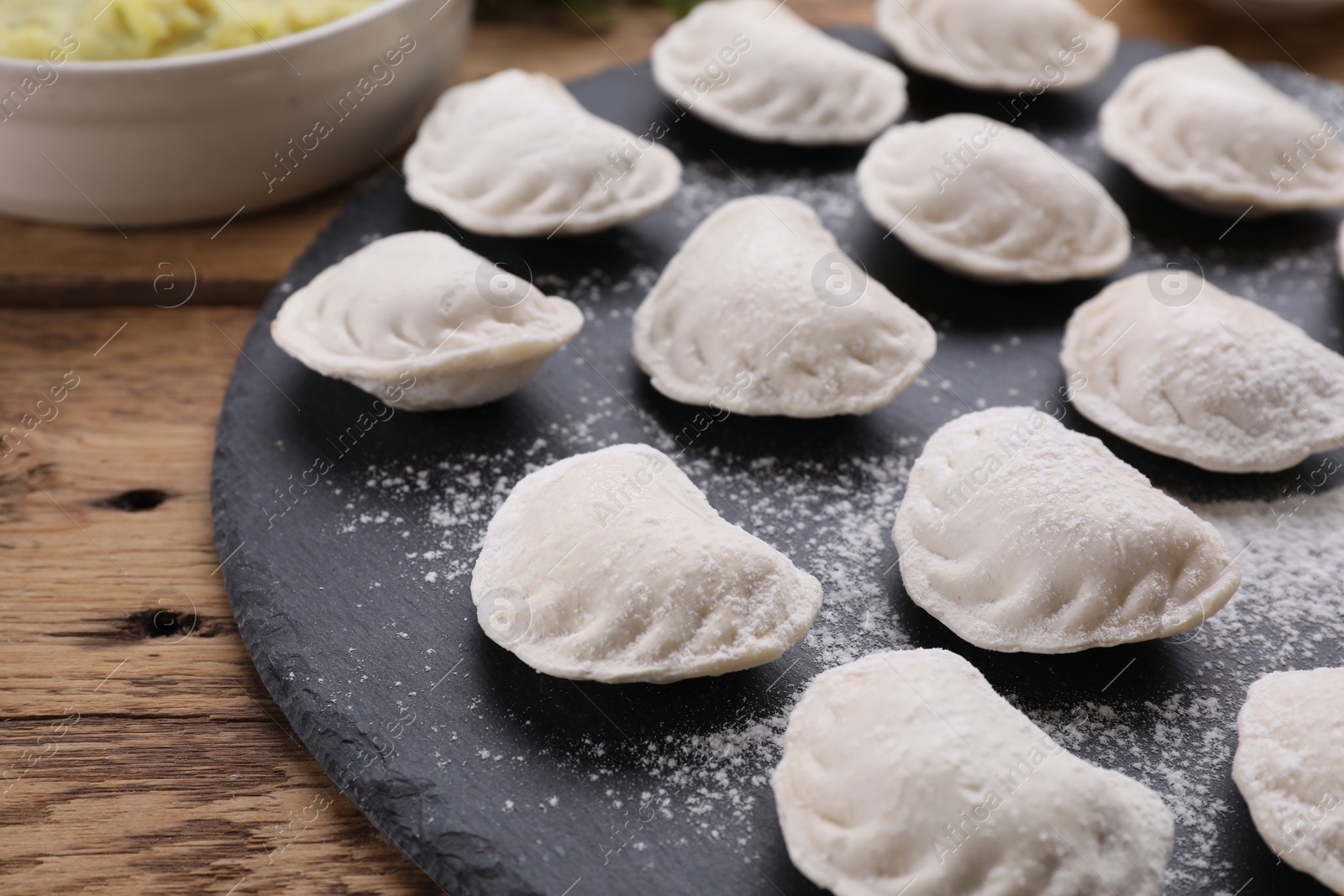 Photo of Raw dumplings (varenyky) on wooden table, closeup