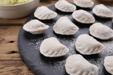 Photo of Raw dumplings (varenyky) on wooden table, closeup