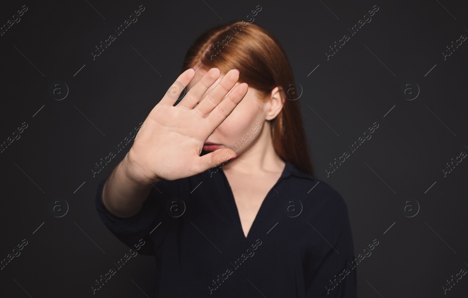 Photo of Young woman making stop gesture against dark background, focus on hand