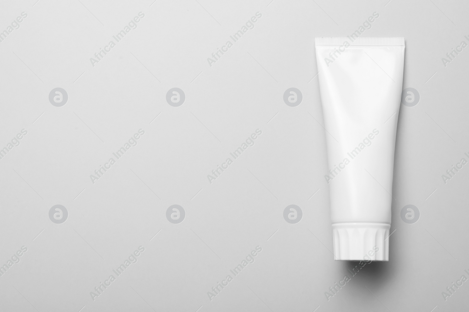 Photo of Blank tube of toothpaste on white background, top view with space for text