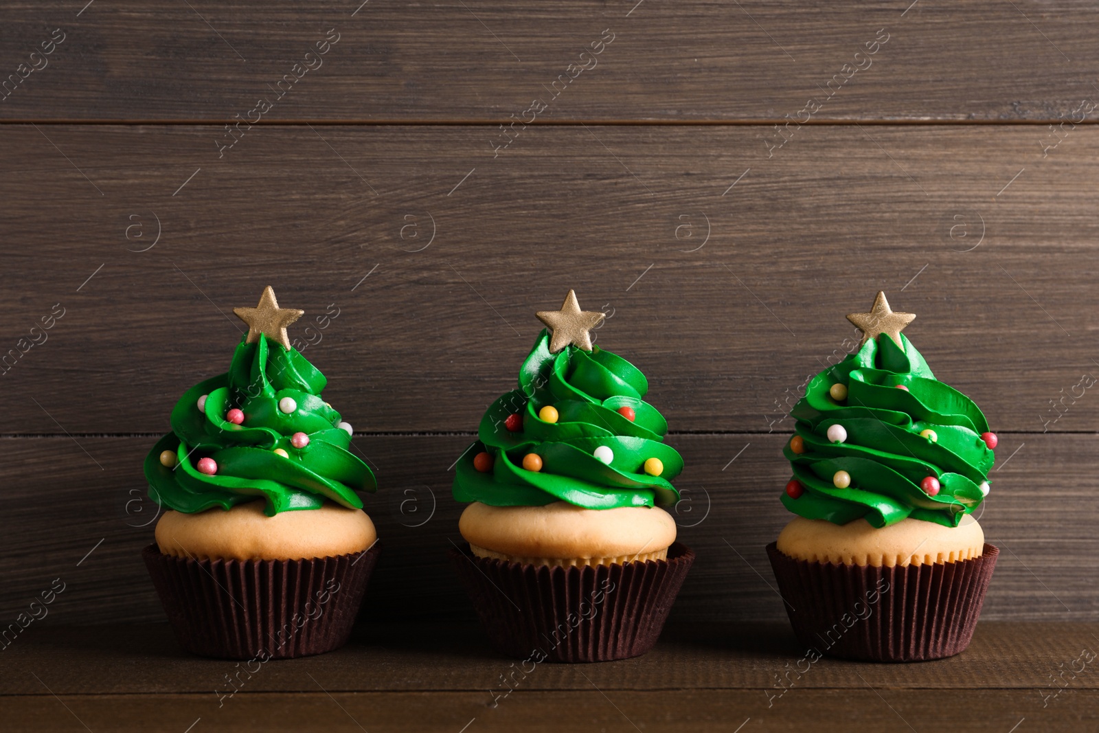 Photo of Christmas tree shaped cupcakes on wooden table