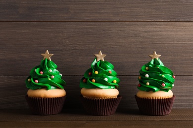 Photo of Christmas tree shaped cupcakes on wooden table