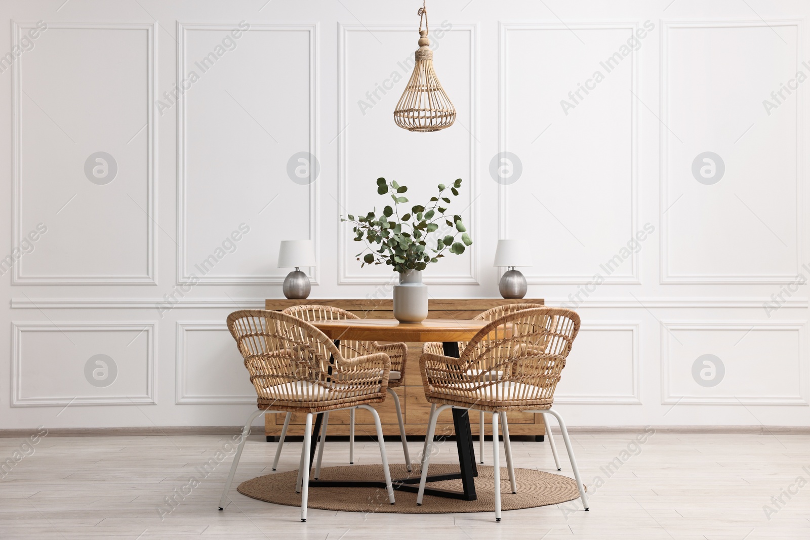 Photo of Dining room interior with comfortable furniture and eucalyptus branches