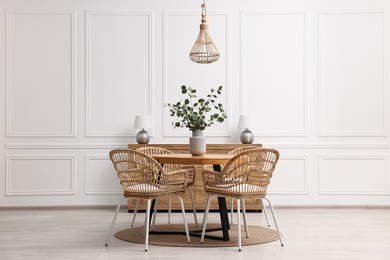 Photo of Dining room interior with comfortable furniture and eucalyptus branches