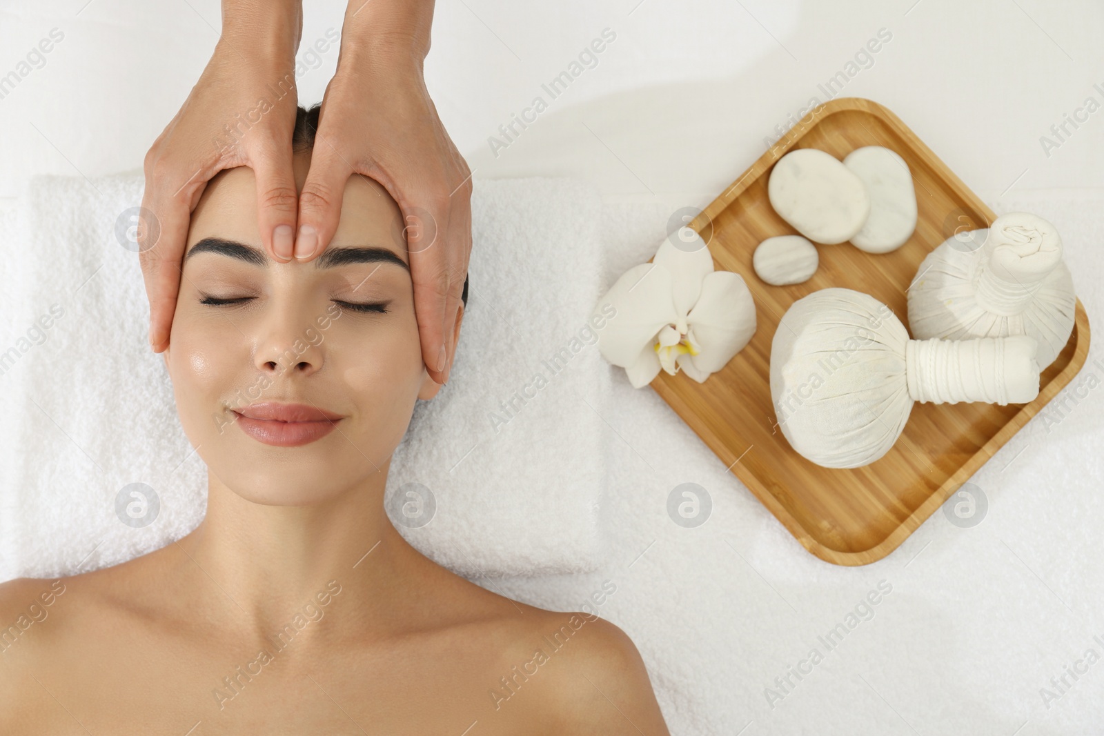 Photo of Young woman receiving facial massage in spa salon, top view