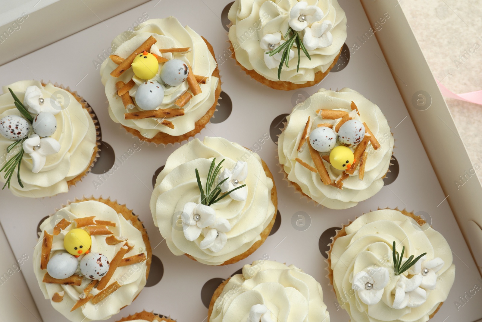 Photo of Tasty Easter cupcakes in box on table, top view