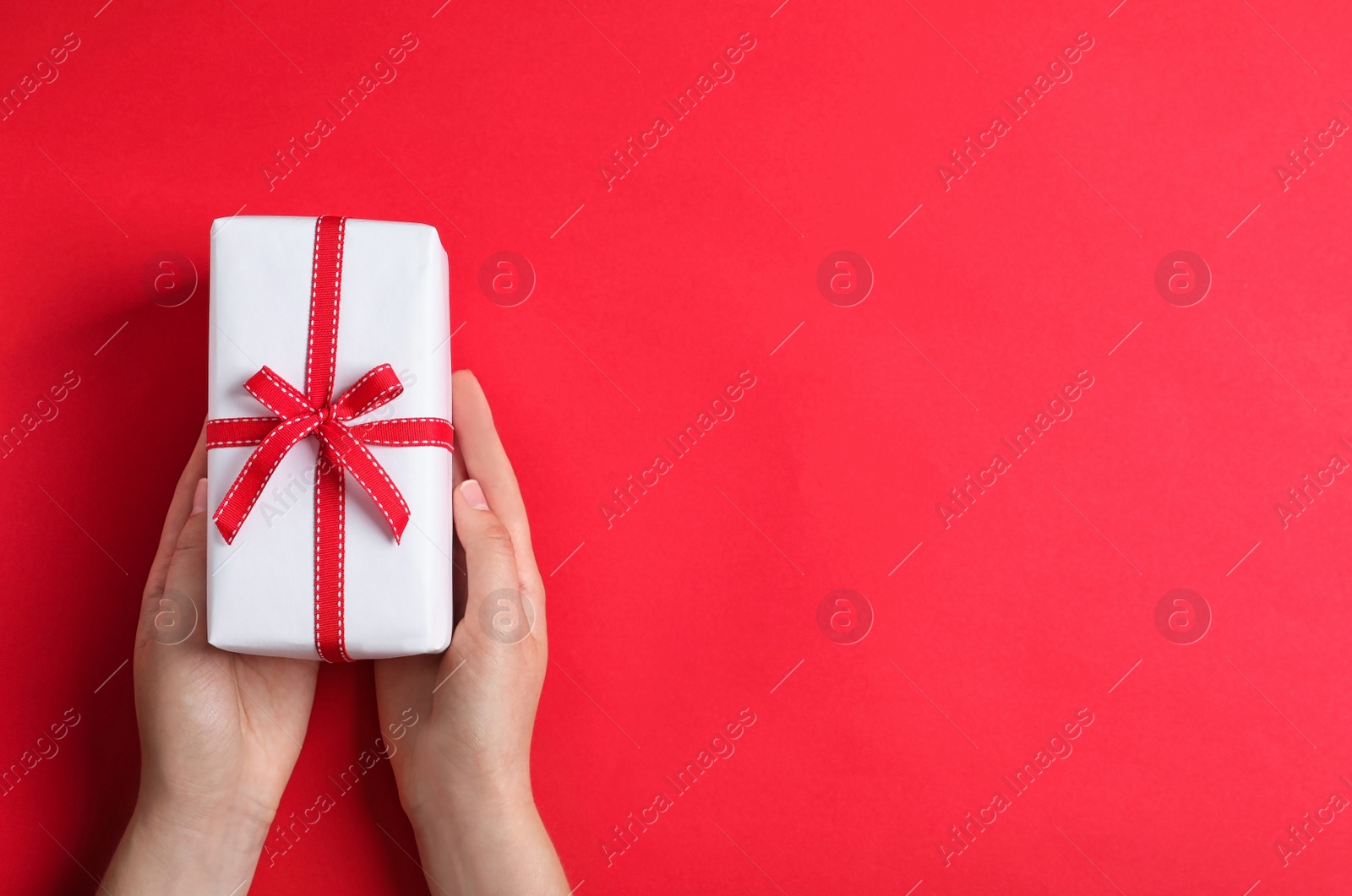 Photo of Woman holding gift box on color background, top view