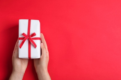 Photo of Woman holding gift box on color background, top view