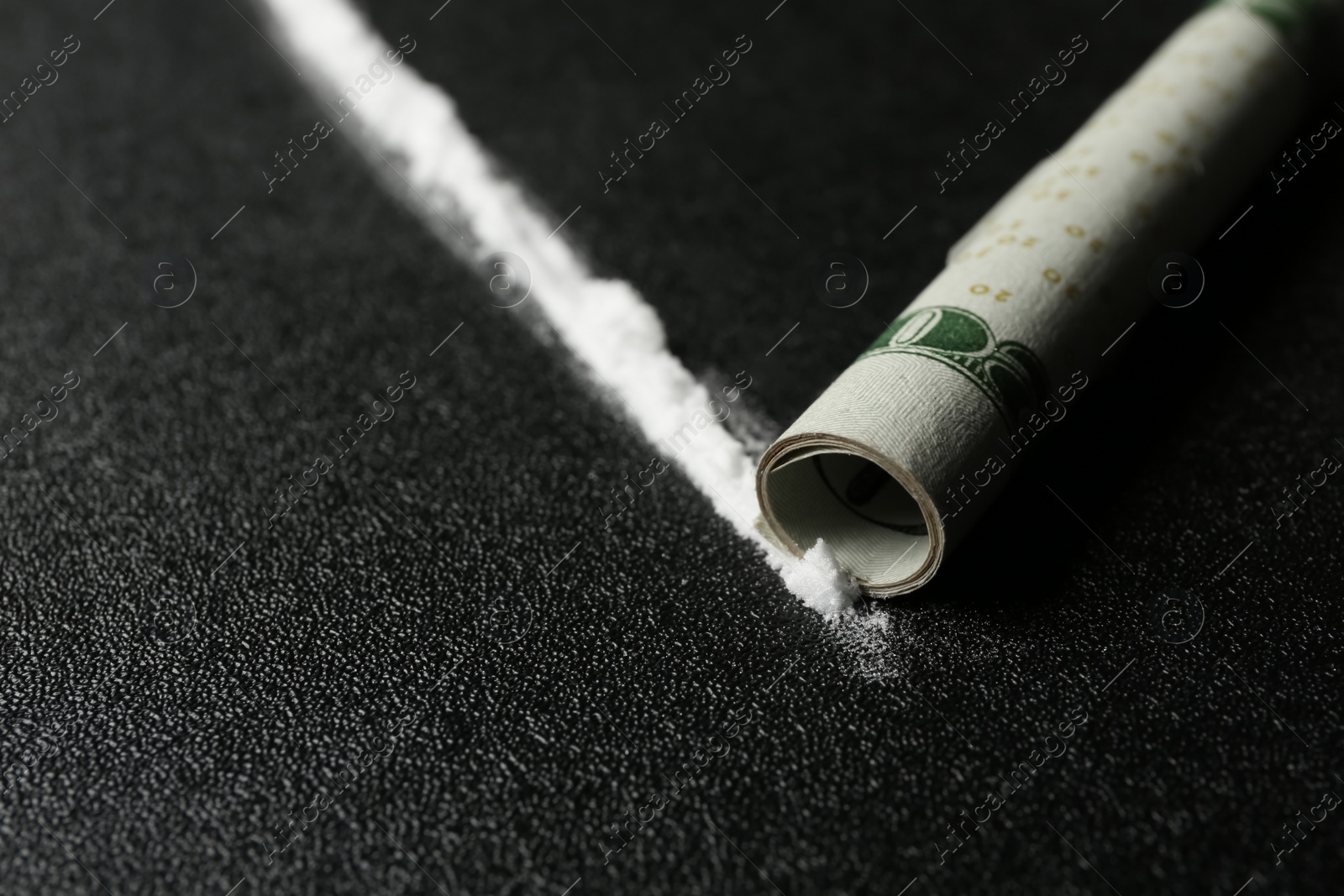 Photo of Line of cocaine and rolled money bill on dark background, closeup