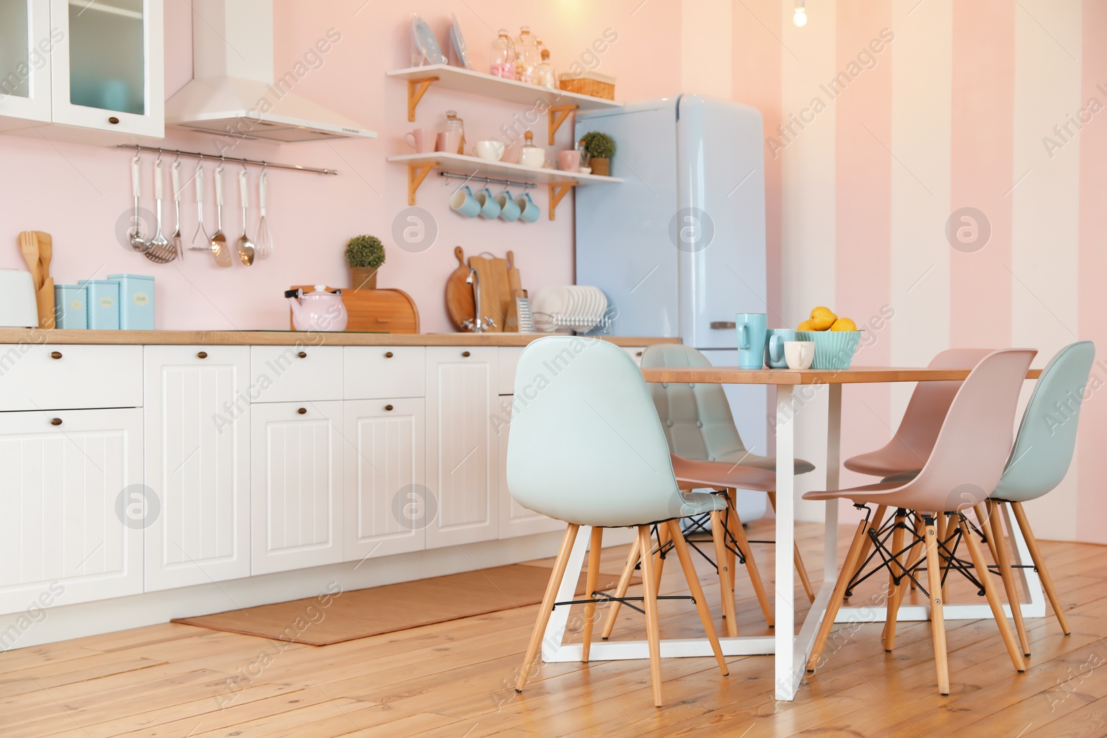 Photo of Stylish pink kitchen interior with dining table and chairs