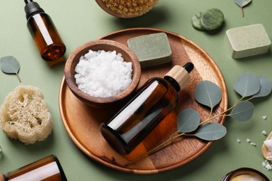 Composition with different spa products and eucalyptus branches on olive background, above view