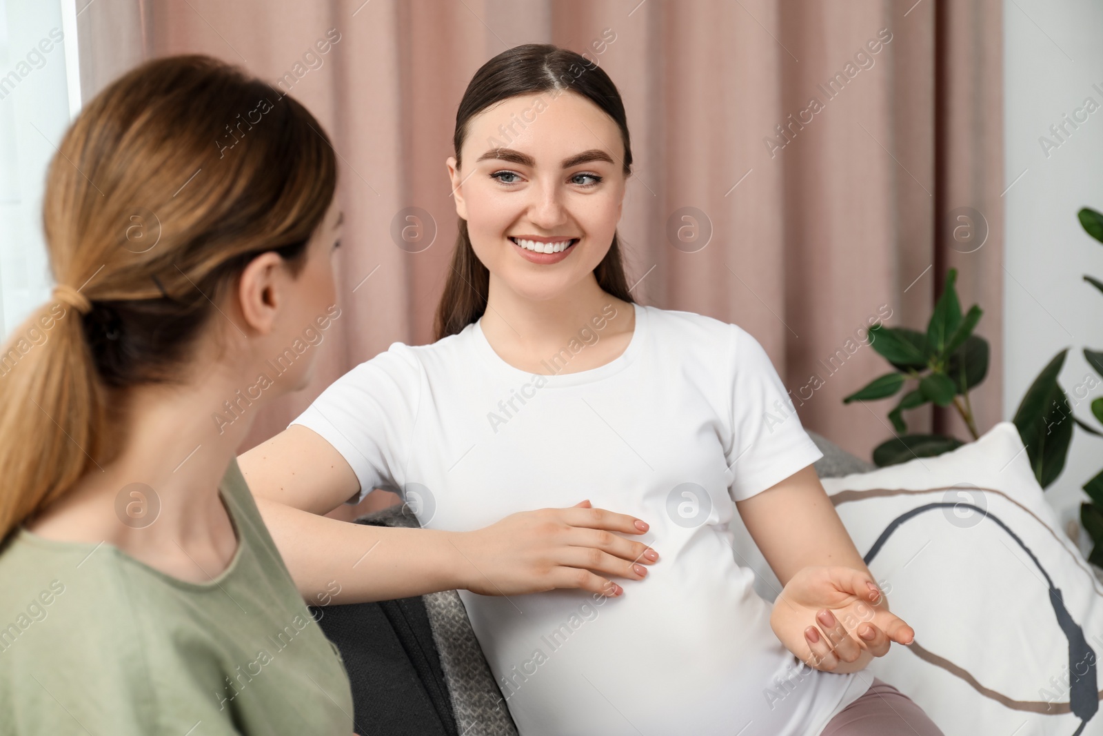 Photo of Doula working with pregnant woman on sofa at home. Preparation for child birth