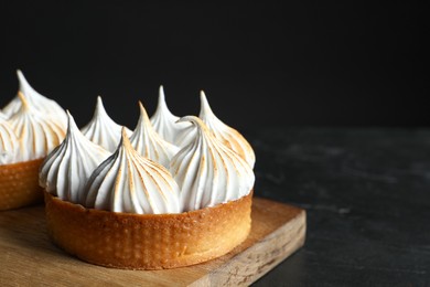 Photo of Tasty dessert. Tartlets with meringue on black table, closeup. Space for text