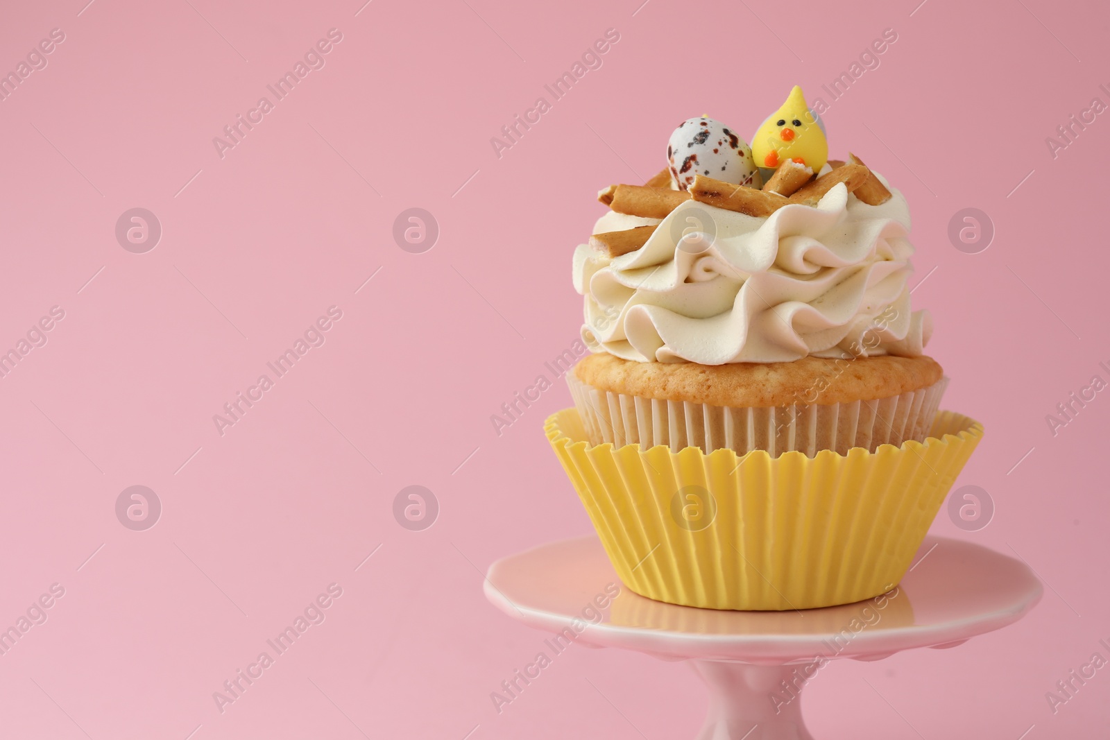 Photo of Tasty Easter cupcake with vanilla cream on pink background, space for text