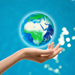 Image of Woman holding icon of Earth on blue background, closeup. Ecology concept