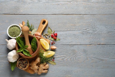 Photo of Different natural spices and herbs on grey wooden table, flat lay. Space for text