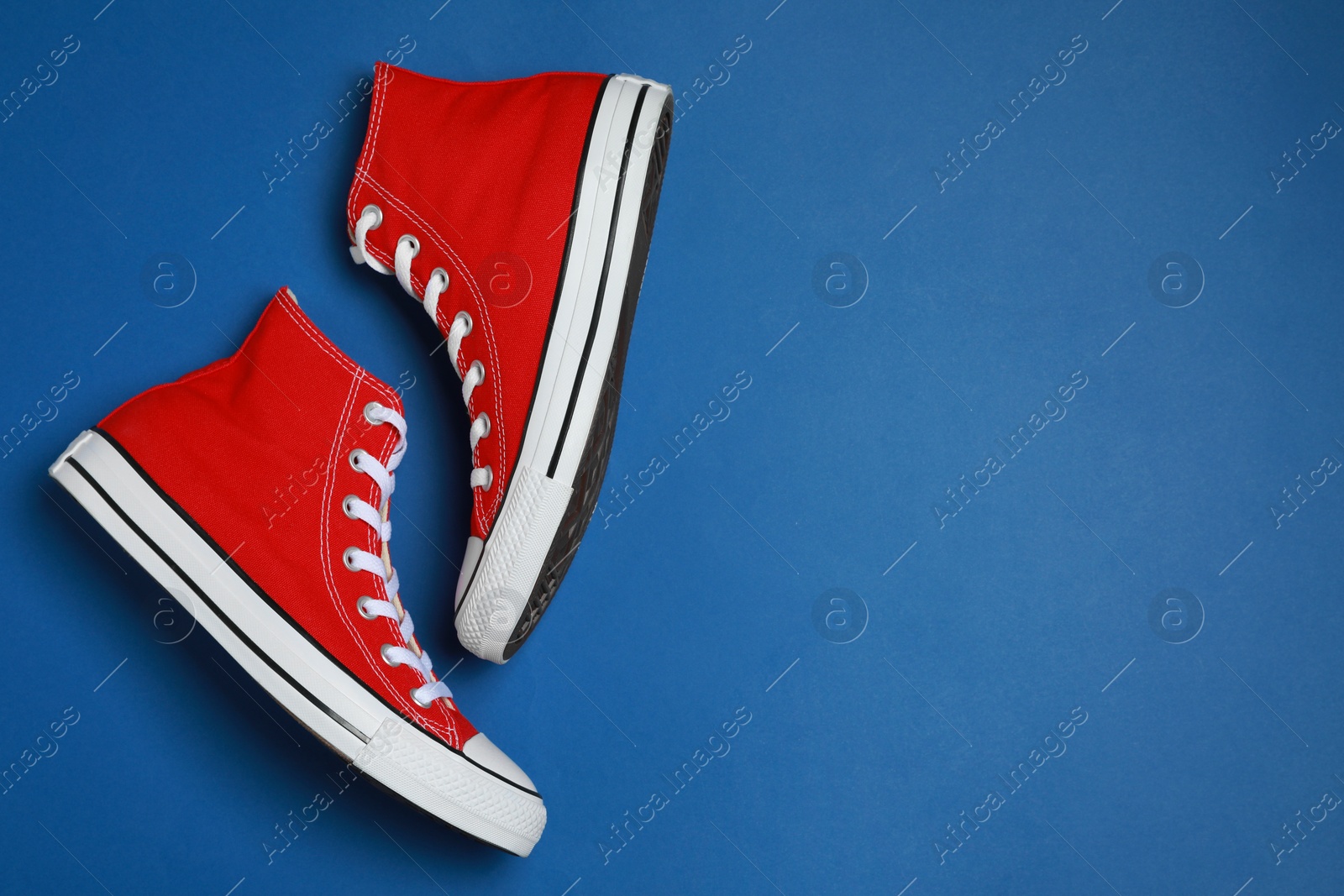 Photo of Pair of new stylish red sneakers on blue background, flat lay. Space for text