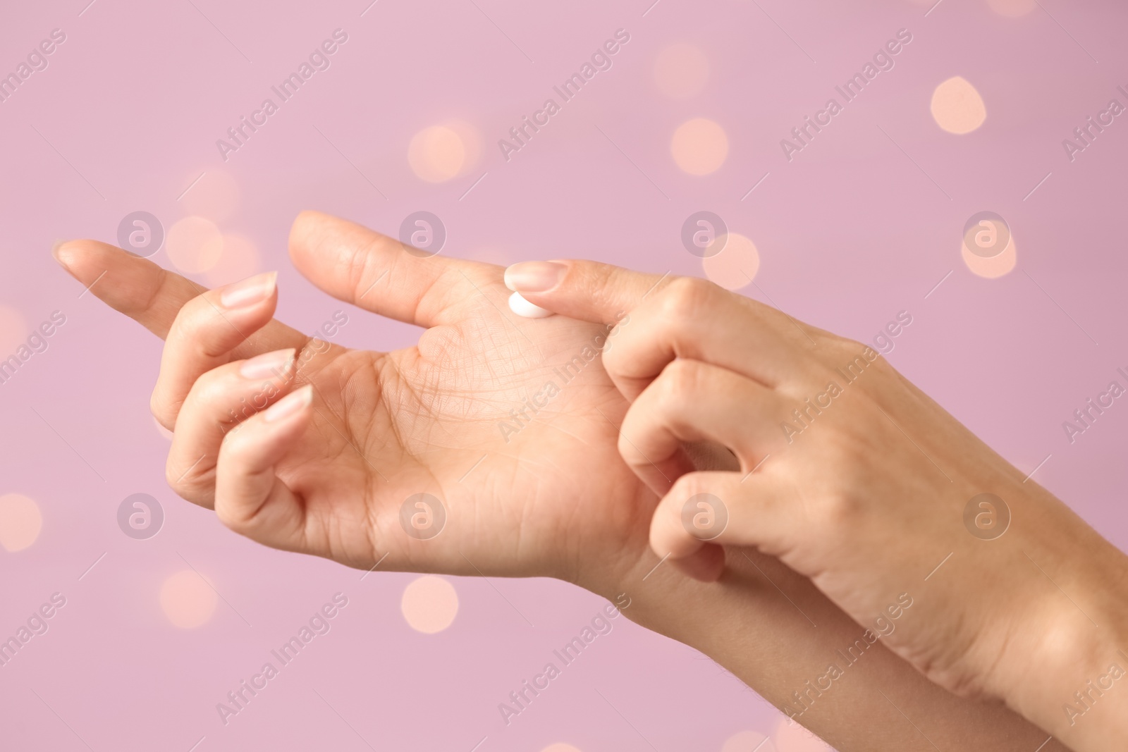 Photo of Woman applying hand cream on blurred background, closeup