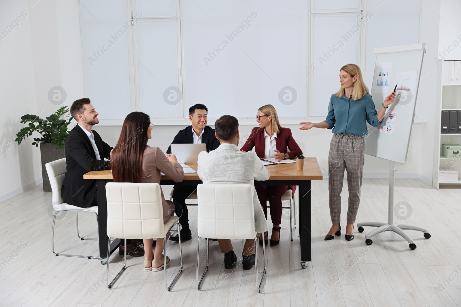 Photo of Businesswoman showing charts near flipchart on meeting in office