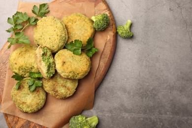 Photo of Delicious vegan cutlets with broccoli and parsley on light gray table, top view. Space for text