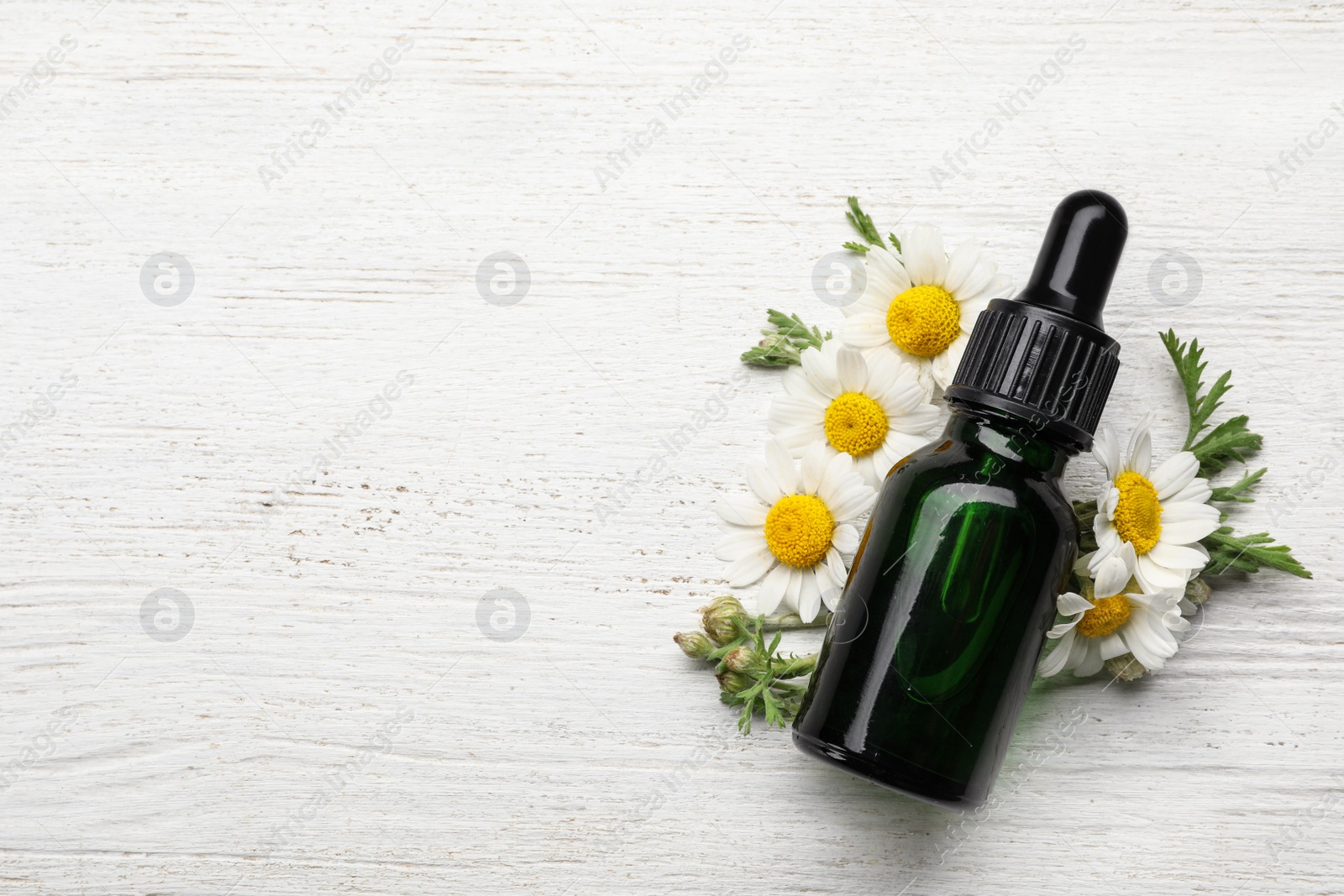 Photo of Flat lay composition with bottle of chamomile essential oil and space for text on white wooden background