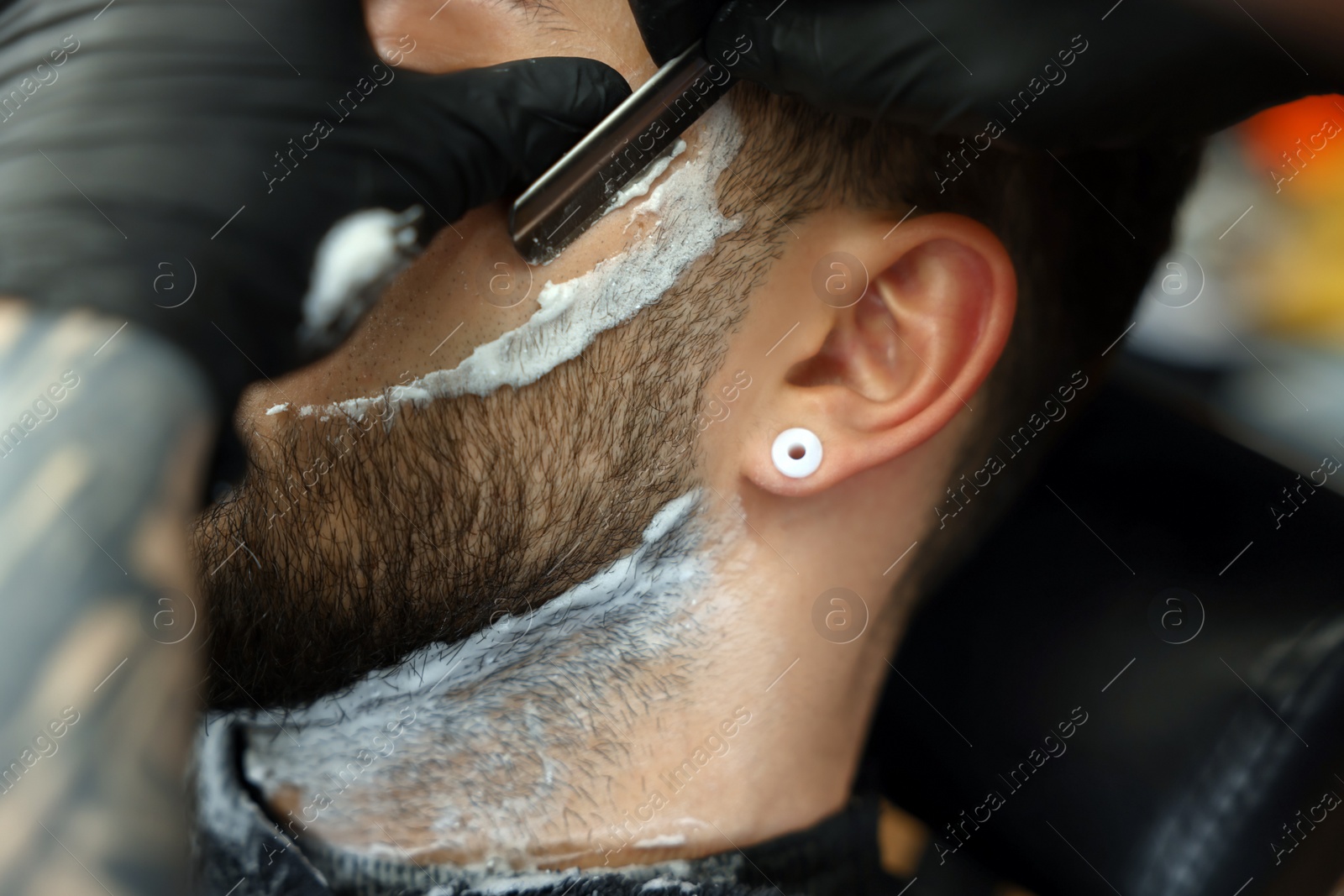 Photo of Professional hairdresser working with bearded client in barbershop, closeup