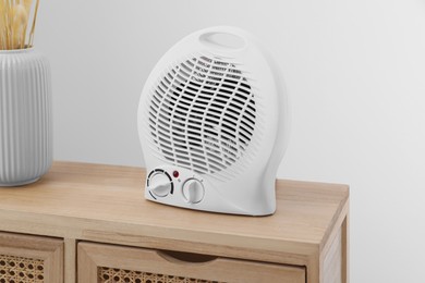 Photo of Electric fan heater on wooden cabinet indoors
