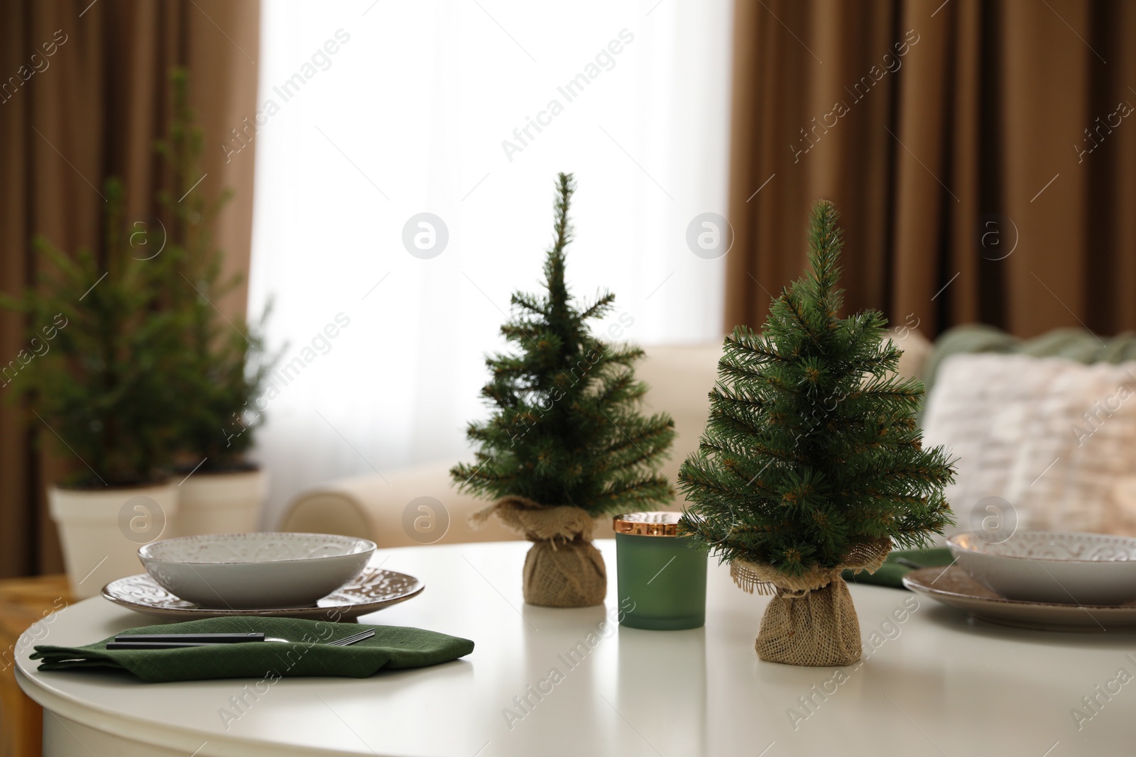 Photo of Small fir trees on dining table indoors. Christmas interior design