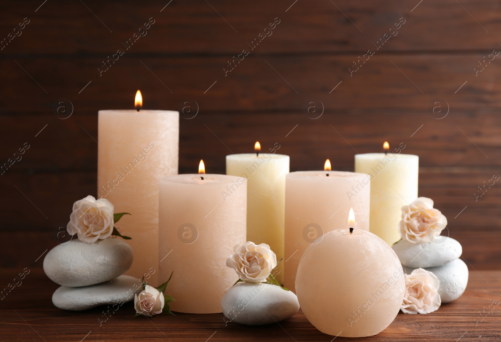 Photo of Composition of burning candles, spa stones and flowers on table. Space for text